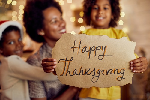 family celebrating thanksgiving holding happy thanksgiving sign